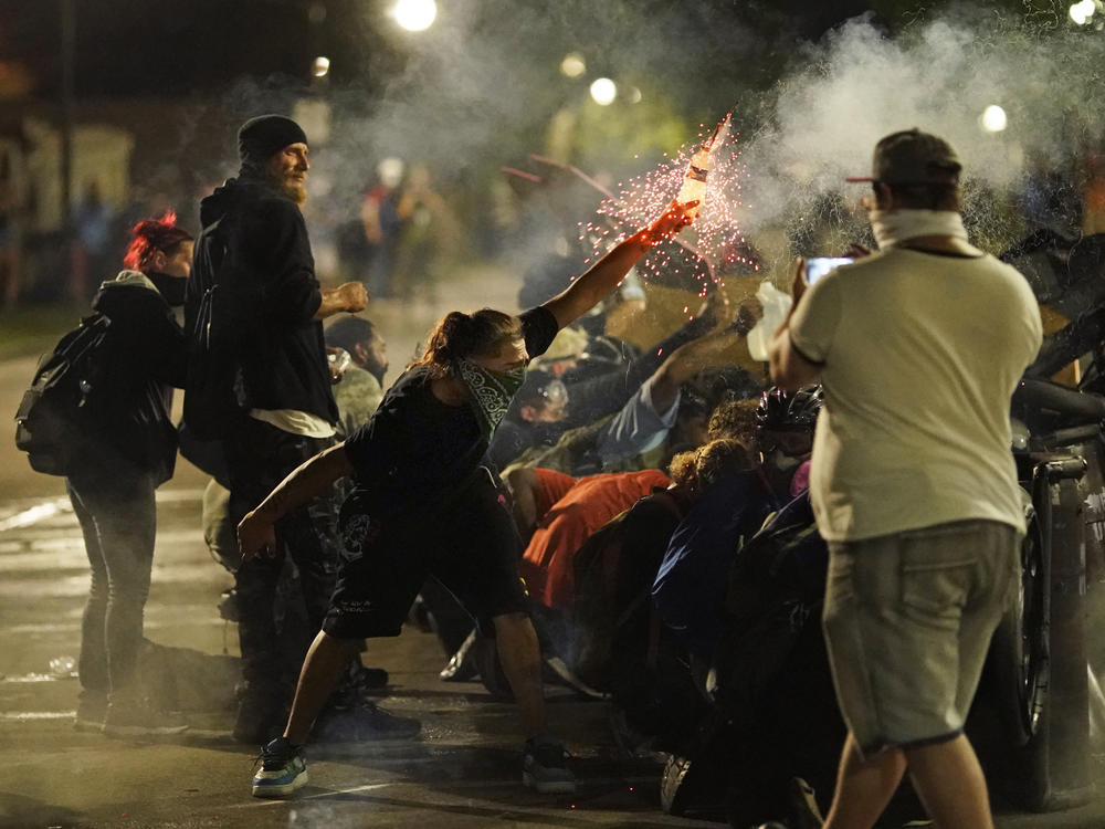 A protester thrusts an object toward police during clashes outside the courthouse late Tuesday during the third night of unrest in the city.