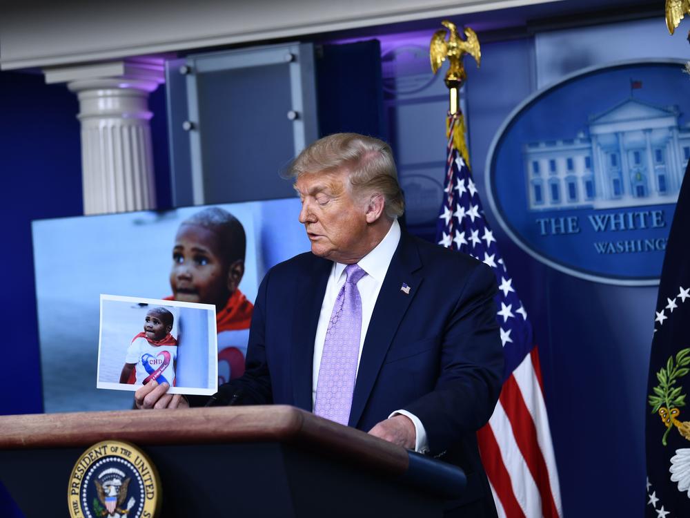 President Trump holds a photo of LeGend Taliferro, a boy killed in Kansas City, Mo., during a White House news conference.