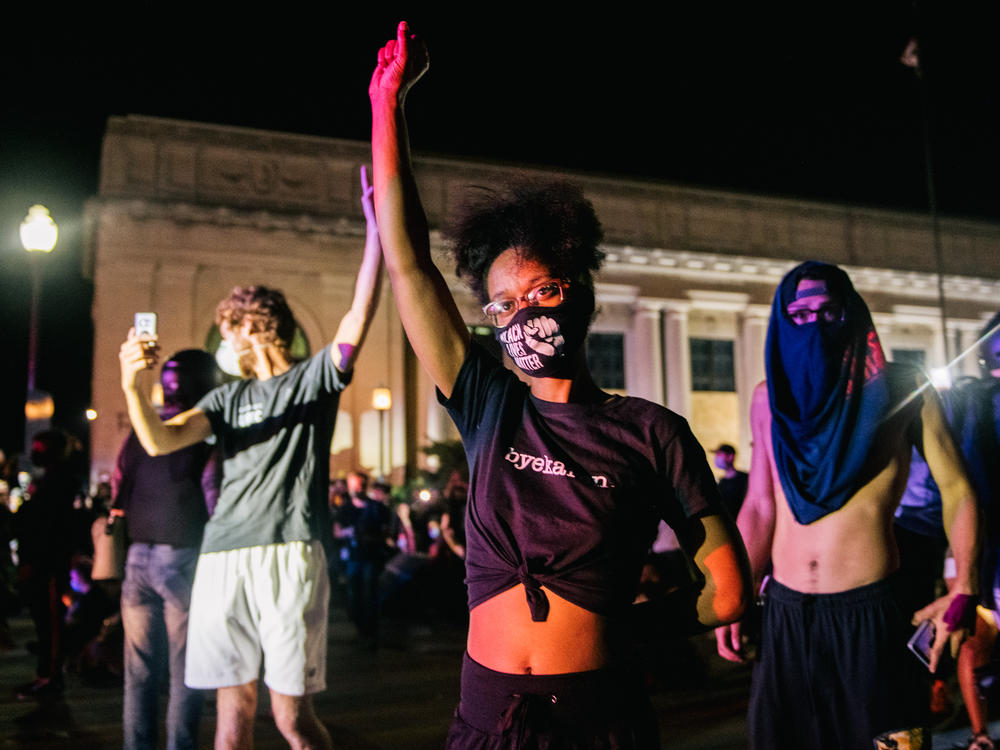 Demonstrators raise their fists in the air on Tuesday in Kenosha, Wis. It was the third night of protests in the city following the police shooting of Jacob Blake on Sunday.