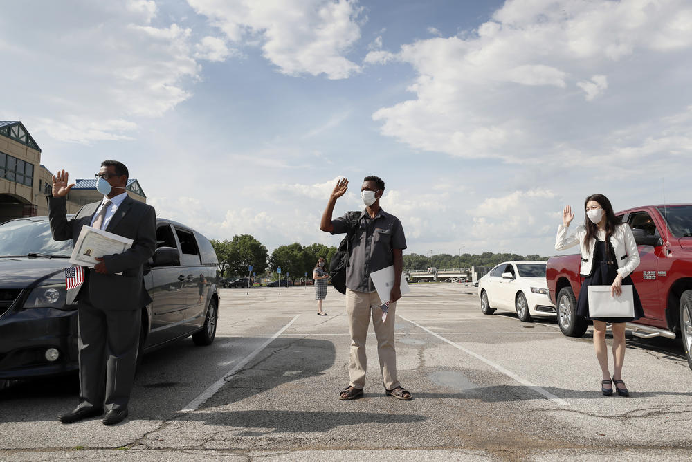 (Left to right) Maweya Babekir, Mulugeta Turuneh and June Yoon Kranci take the U.S. oath of allegiance during a drive-through naturalization ceremony on June 26 at Principal Park in Des Moines.