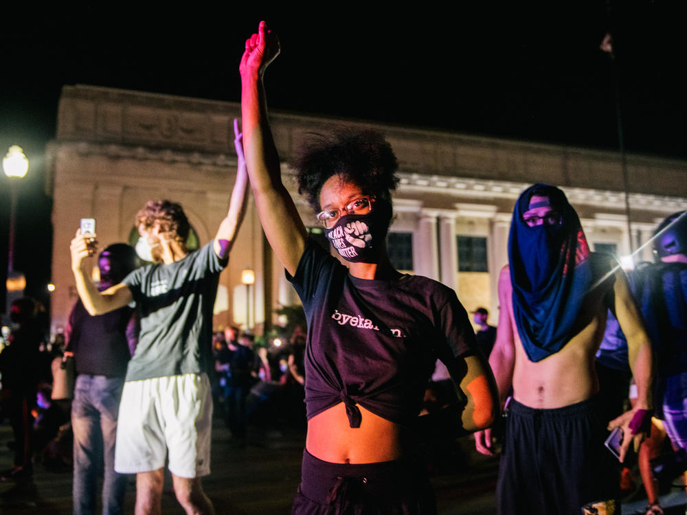 Protesters raise their fist in the air in front of law enforcement last month in Kenosha, Wis., after the police shooting of Jacob Blake.