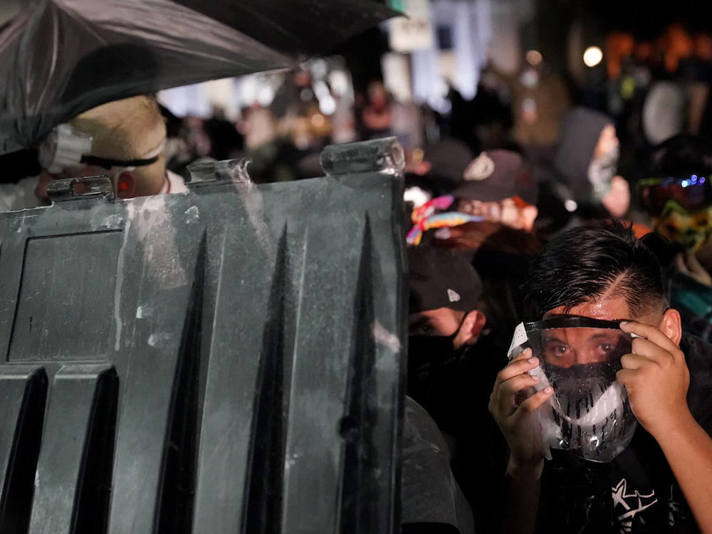 A protester takes cover during clashes outside the Kenosha County Courthouse late Tuesday in Kenosha, Wis.