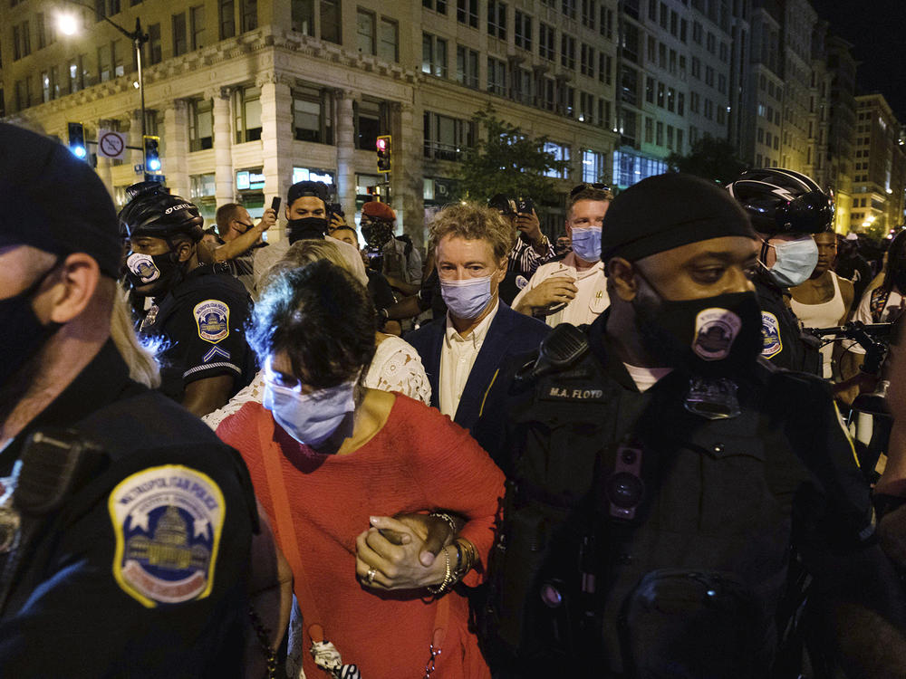 Sen. Rand Paul, R-Ky., center, and others receive a police escort upon leaving President Trump's acceptance speech Thursday night at the White House. A crowd surrounded Paul and his wife, demanding that the senator acknowledge  Breonna Taylor.