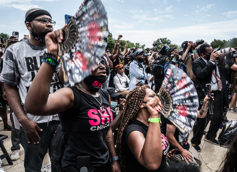 Attendees of the march try to cool off with fans.