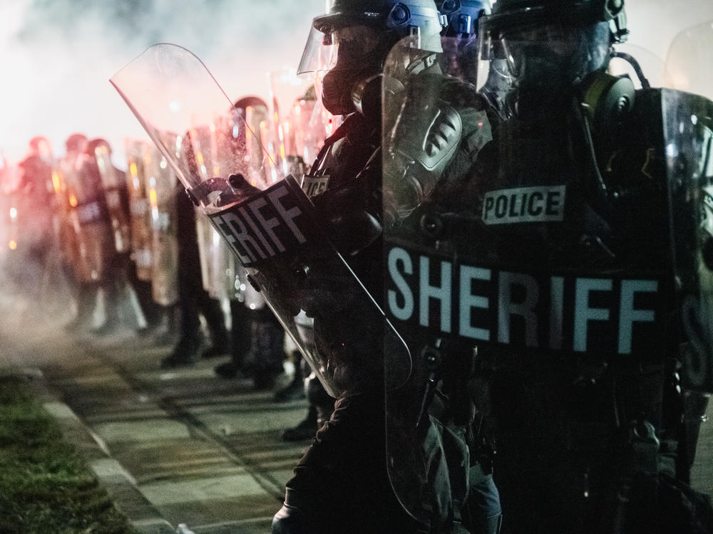 Law enforcement holds a line Tuesday in Kenosha, Wis. The union representing police officers in Kenosha says Jacob Blake, who was shot multiple times at close range and severely wounded by a police officer, was armed with a knife.