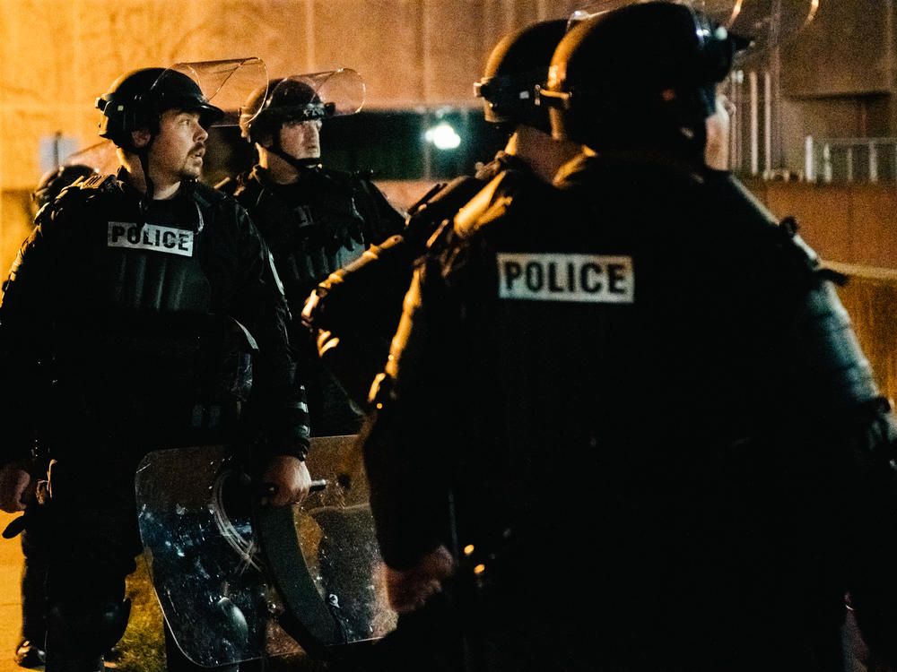 Police officers stand guard inside of a fenced area that surrounds several government buildings in Kenosha, Wis., on Thursday.