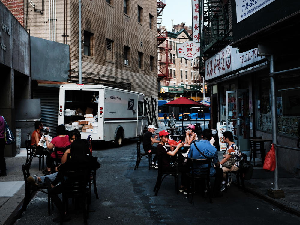 People eat in an outdoor dining area in New York City's Chinatown on Aug. 10. Economists warn spending may suffer this month.