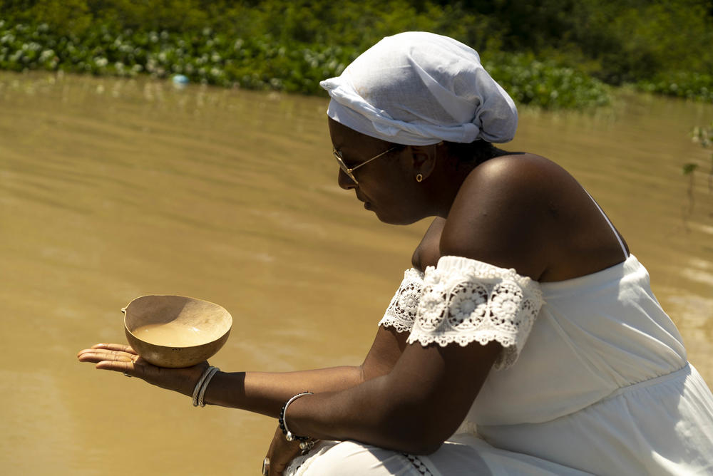During a visit to Suriname, Peggy Bouva pours almond syrup from a dried gourd as part of a prayer for Philida, Johanna and Rosalina Bouva, three ancestors enslaved by the Dutch. Bouva spent two years researching her family's history together with Dutch radio producer Maartje Duin, whose ancestor held stock in the plantation where Bouva's relatives where enslaved.