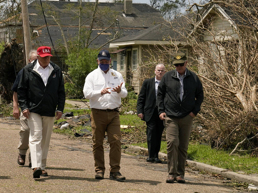 President Trump listens to Louisiana Gov. John Bel Edwards, center, as he tours damage from Hurricane Laura, in Lake Charles, La.