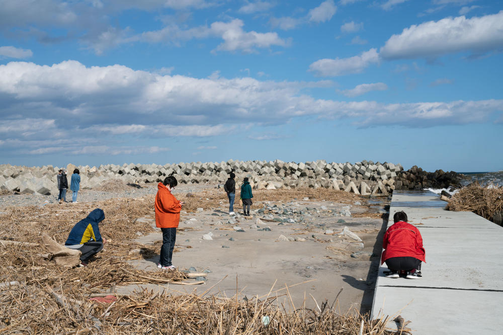 People stand near the ocean in Japan's Fukushima prefecture, commemorating the ninth anniversary of the tsunami and nuclear disaster.