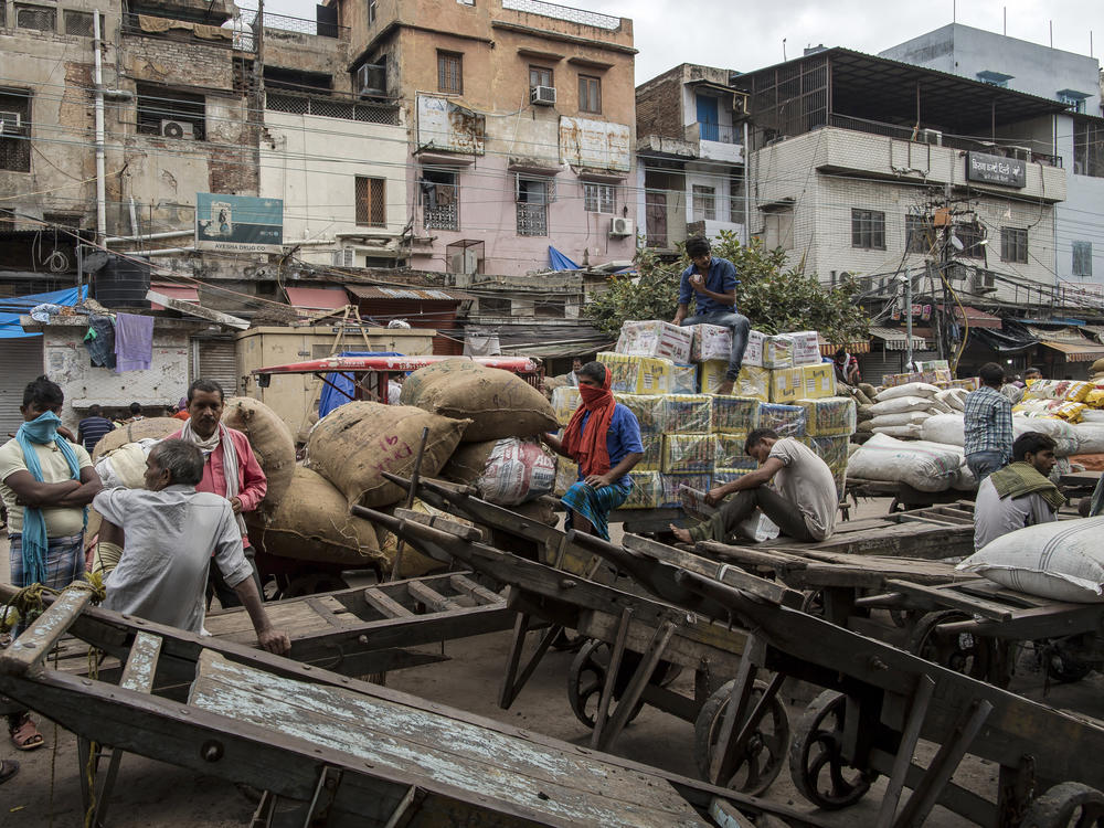 Workers and day laborers gather outside shuttered stores Monday in New Delhi. Once the world's fastest-growing major economy, India posted its steepest decline in gross domestic product in 24 years.