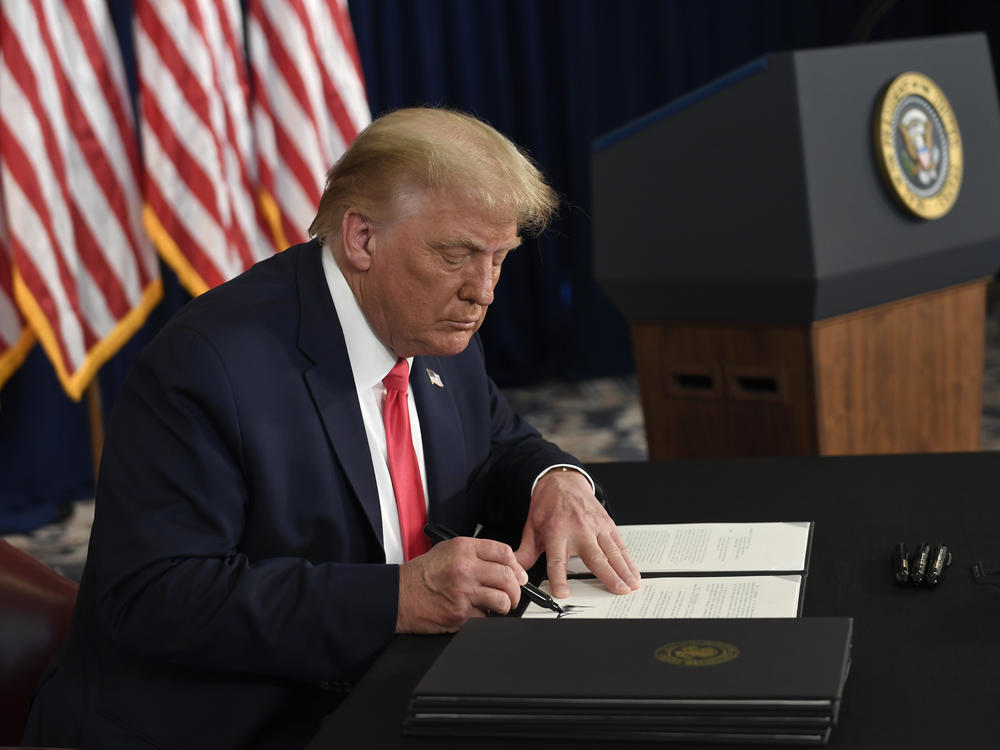 President Trump signs one of four executive orders addressing the economic fallout from the pandemic in Bedminster, N.J., on Aug. 8. The Trump administration has given employers the option to stop collecting payroll taxes, but workers may have to repay the money next year.