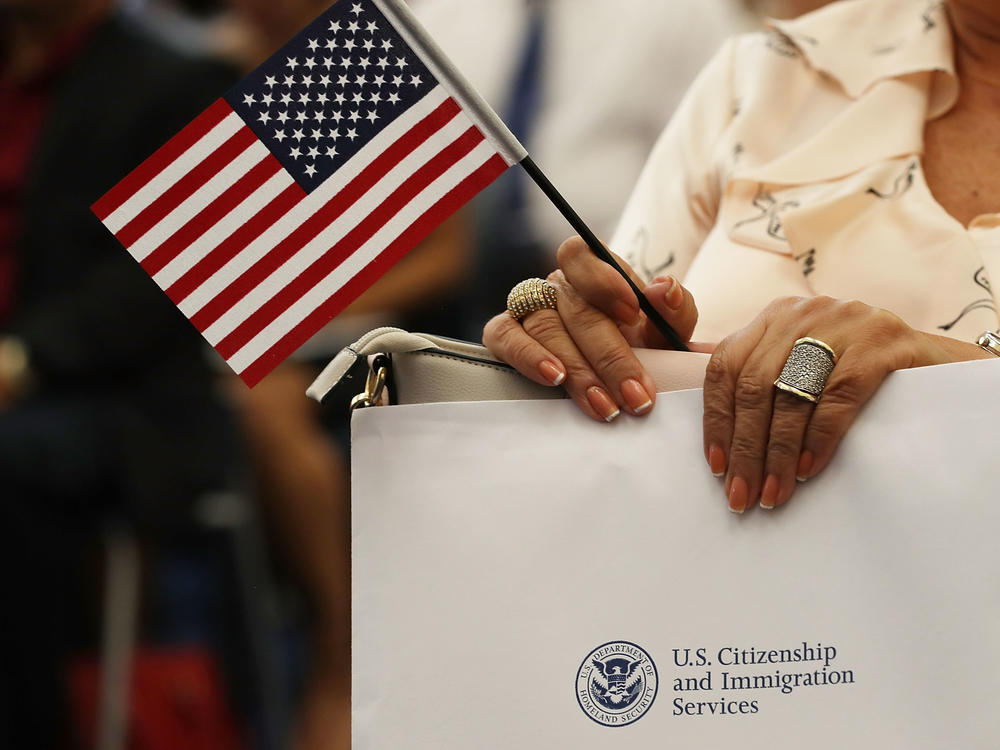 An attendee holds an American flag at a U.S. Citizenship & Immigration Services naturalization ceremony in Miami, Fla. in Aug. 2018. The Trump administration is considering expanding its collection of biometric data as part of the immigration process.