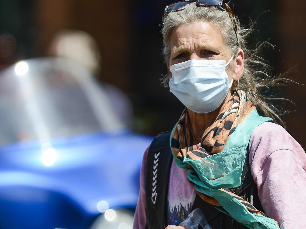 A woman crosses the street as motorcyclists ride through Deadwood, South Dakota during the Sturgis Motorcycle Rally. Despite the pandemic this years rally drew nearly half a million attendees.