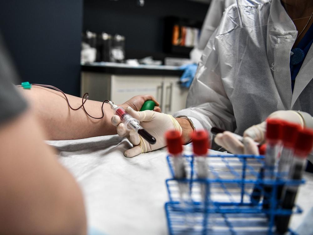 A researcher takes blood samples from a patient as she participates in a COVID-19 vaccine study last month at the Research Centers of America in Hollywood, Fla.