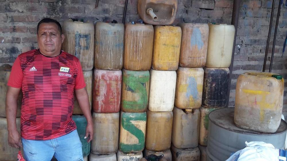Álvaro Albarracín stands beside jugs used to smuggle gasoline from Venezuela into Colombia. He's pictured at a warehouse in Cúcuta he built after a fire destroyed his old one.