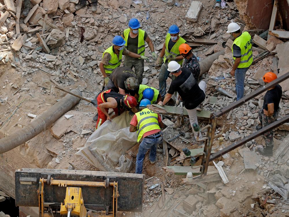 Rescue workers dig through the rubble of a badly damaged building in Lebanon's capital, Beirut, searching for possible survivors a month after a massive blast at the nearby port.
