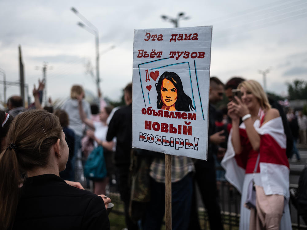 Anti-government protesters hold a sign with a picture depicting Belarusian opposition leader Svetlana Tikhanovskaya as a card that trumps an ace on Aug. 23 in Minsk.