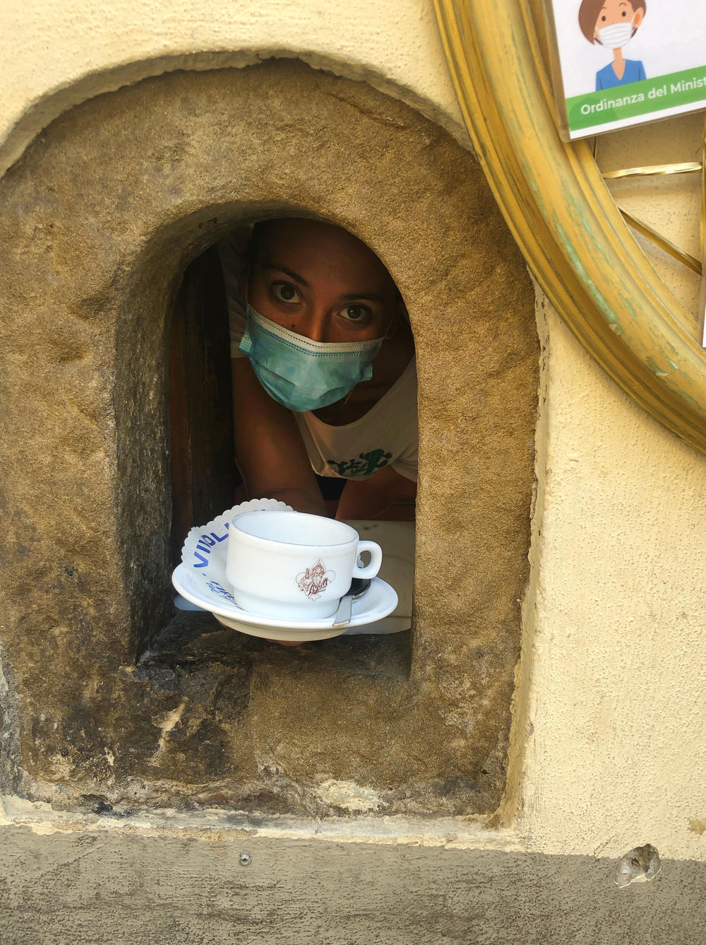 A masked server at the Vivoli cafe's wine window in Florence.