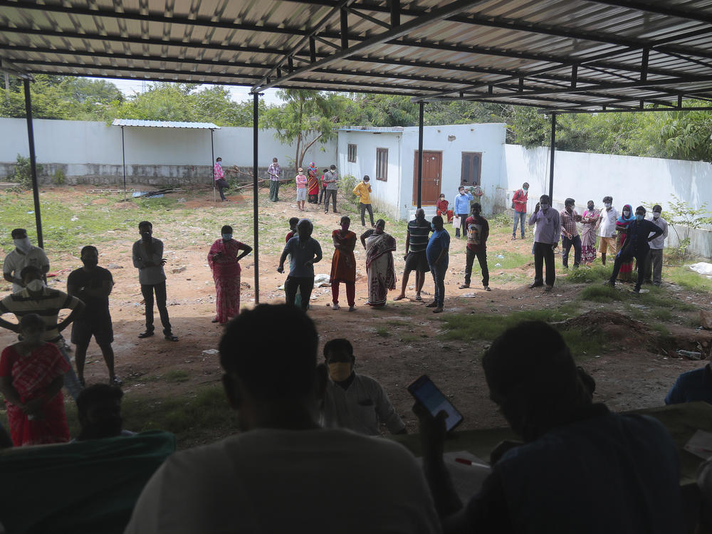 People wait in a queue to register their names before giving their nasal swab samples to test for COVID-19 at a government health center in Hyderabad, India on Saturday. India's coronavirus cases have crossed 4 million.