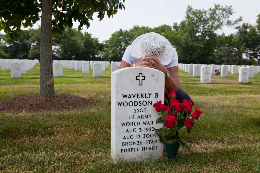 Joann Woodson kneels at the gravesite of her husband, Cpl. Waverly Woodson Jr., at Arlington National Cemetery in Arlington, Va.