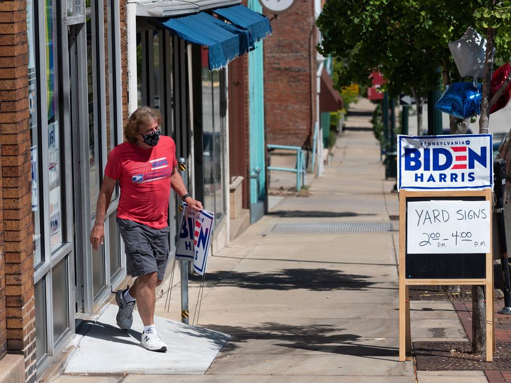 A man walks out of the Washington County Democratic Party office last week, in the suburbs of Pittsburgh, after taking a Joe Biden yard sign. Because of the coronavirus pandemic, Biden's campaign isn't doing any in-person door-knocking.