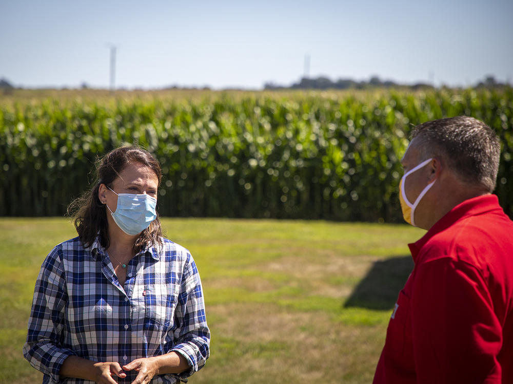 Democrat Theresa Greenfield, a real estate executive from Des Moines, talks with Trent Hatlen, who farms and raises hogs near Rembrandt, Iowa, on Aug. 11.