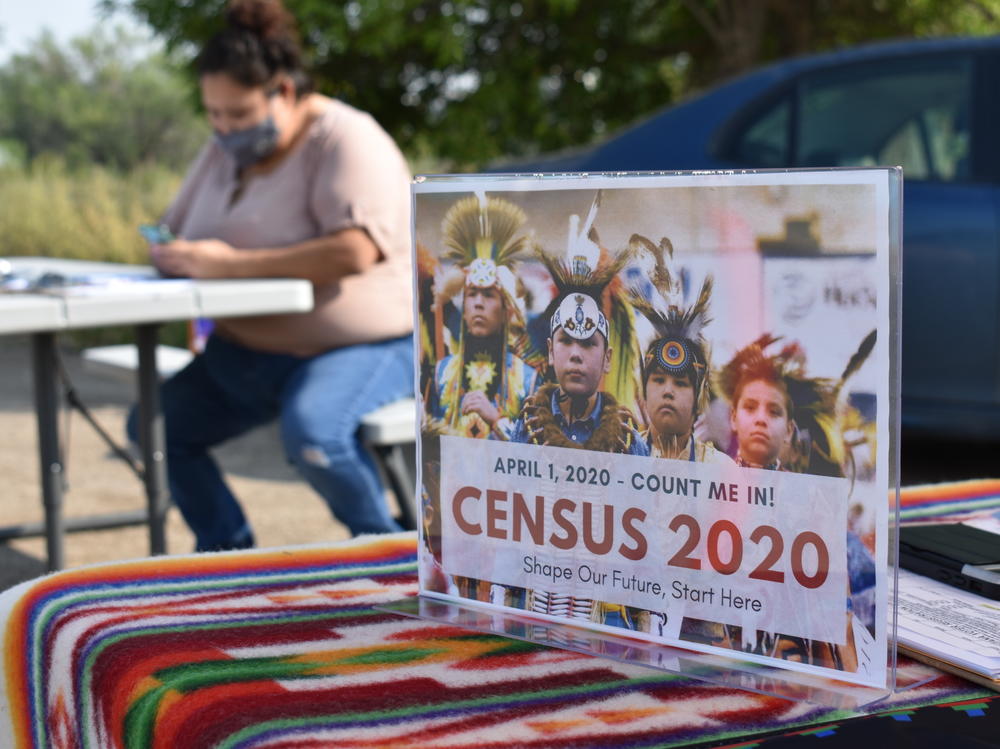 A sign promoting participation in the 2020 census is displayed as Selena Rides Horse enters information into a phone for a member of the Crow Indian Tribe in Lodge Grass, Mont., in August.