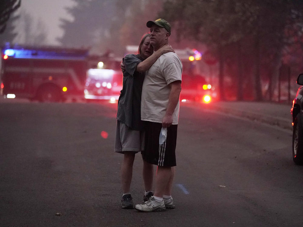 A couple embrace Thursday while touring an area devastated by the Almeda Fire in Phoenix, Ore.
