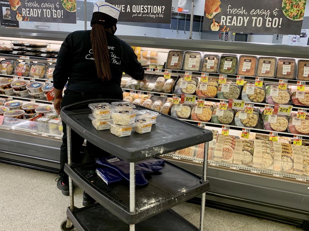 Grocery prices have fallen in recent months but are still 4.6% higher than at this time last year. Here, a woman stock shelves in a deli in June at a Washington, D.C., supermarket.
