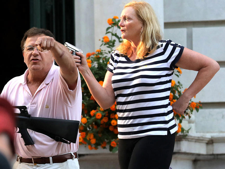 Armed homeowners Mark and Patricia McCloskey confront protesters marching to St. Louis Mayor Lyda Krewson's house on June 28. The St. Louis Metropolitan Police has issued citations for trespassing to nine protesters, and these are under review by the city counselor's office.