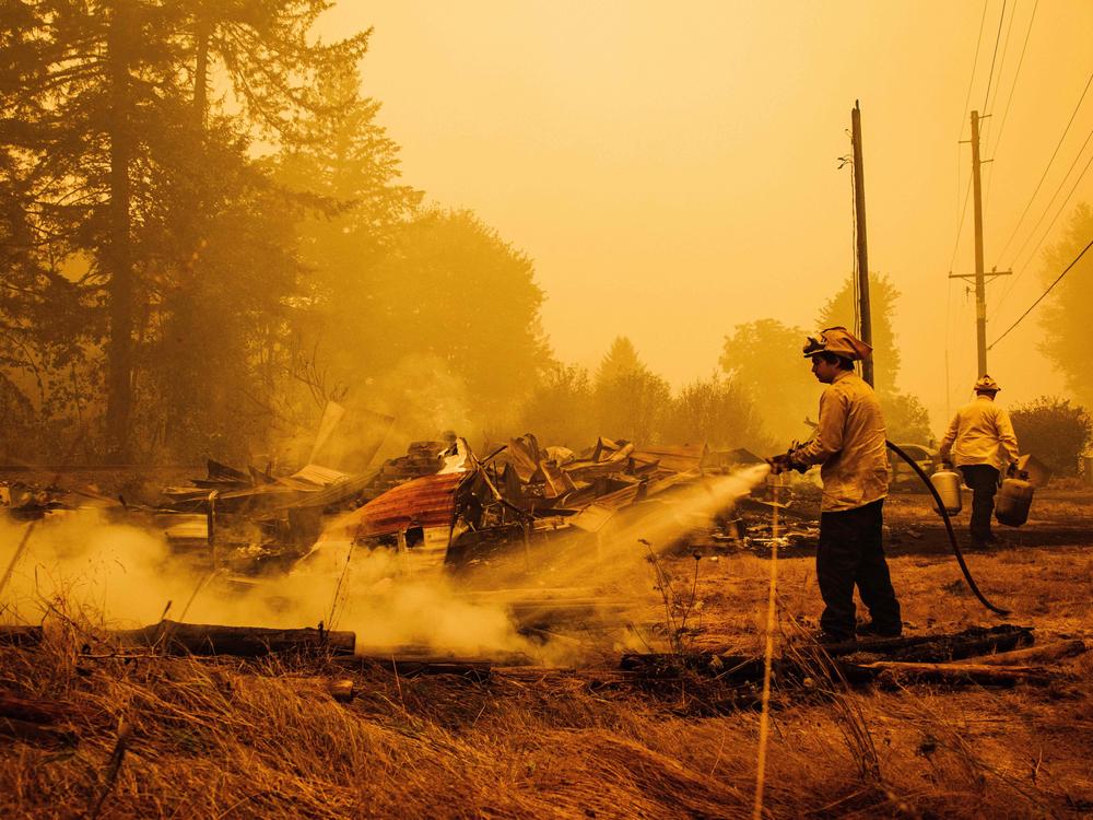 Oregon firefighters put out embers in Mill City, Ore., on Sept. 10, 2020, as they battle the Santiam Fire. As fires ravage the Pacific Northwest, fear and rumors have taken hold on social media.