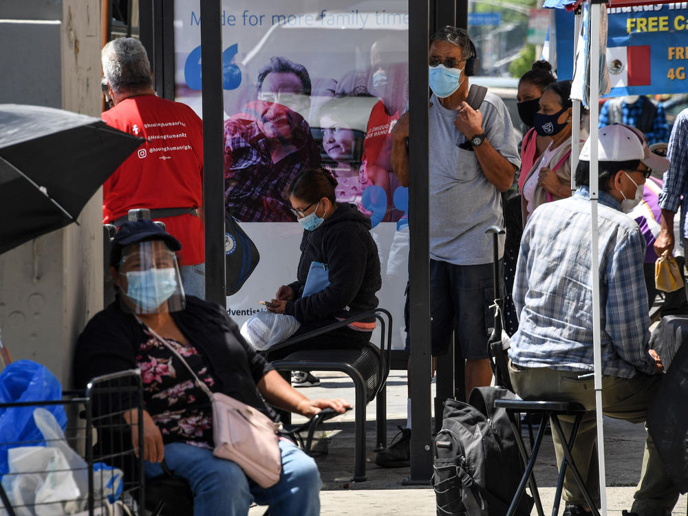 People wait for a bus in August in East Los Angeles. Latinos have the highest rate of labor force participation of any group in California — many in public-facing jobs deemed essential. That work has put them at higher risk of catching the coronavirus.