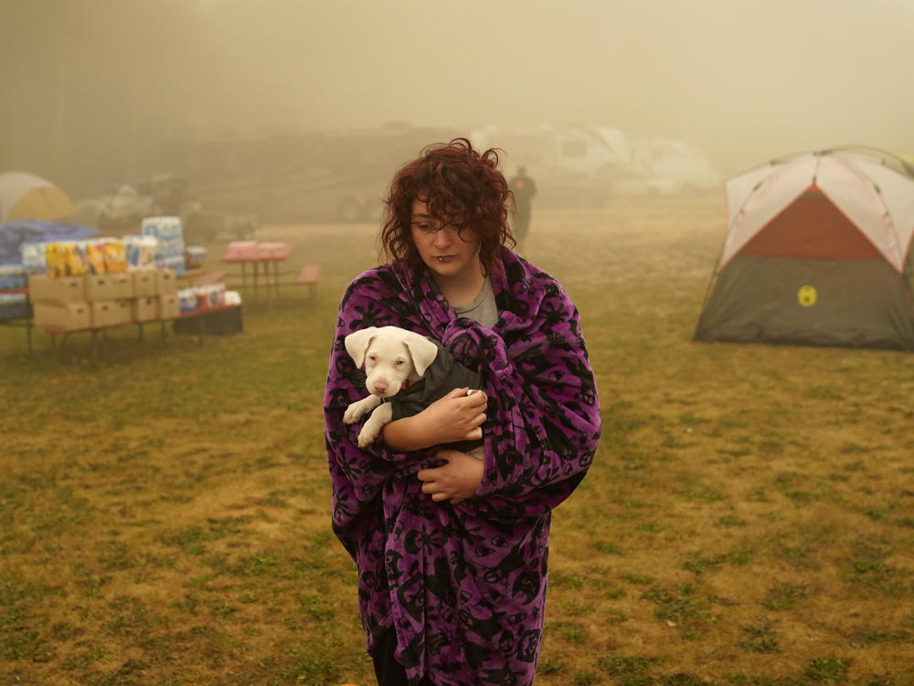 Shayanne Summers holds her dog Toph on Sunday after several days of staying in a tent at an evacuation center at the Milwaukie Portland Elks Lodge in Oak Grove, Ore.