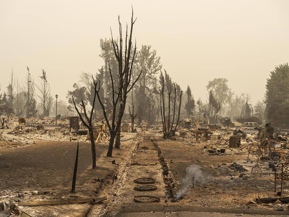 Smoke rises from the ground Sunday in a neighborhood destroyed by wildfire in Talent, Ore.