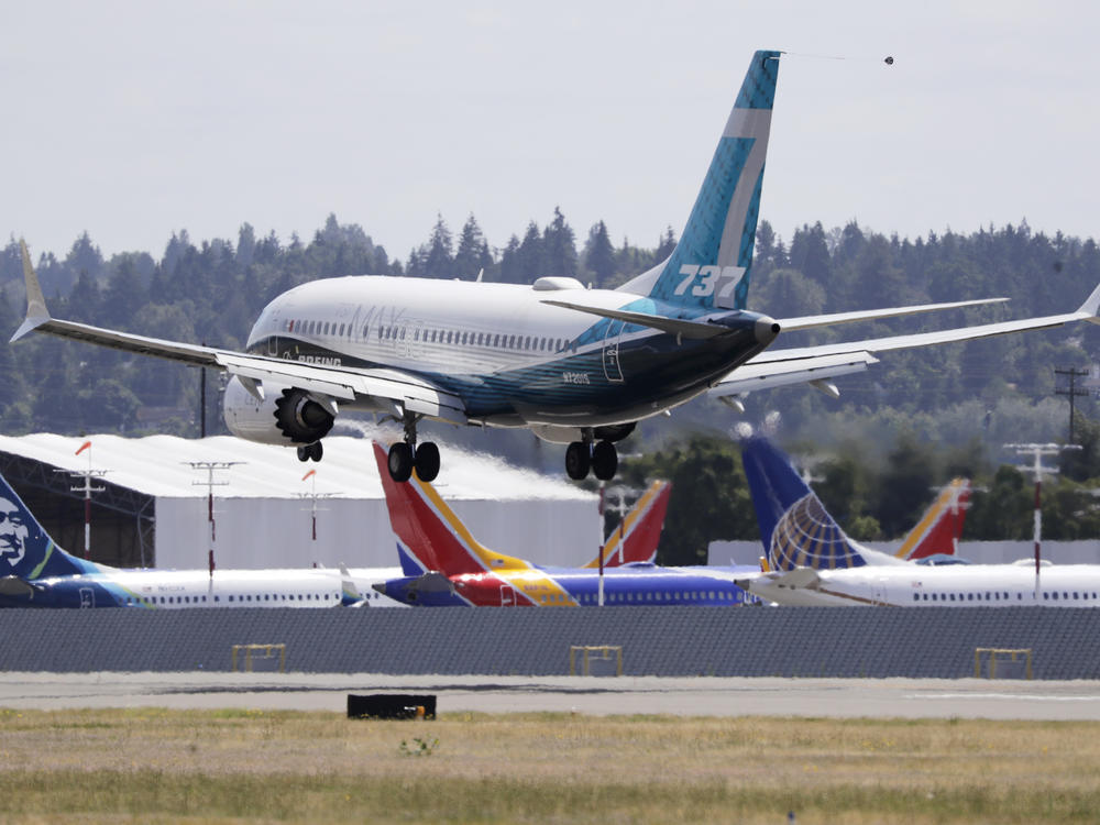 A Boeing 737 Max heads to a landing past grounded Max jets at Seattle's Boeing Field after a test flight in June. It was the first of three days of recertification test flights that mark a step toward returning the aircraft to passenger service.