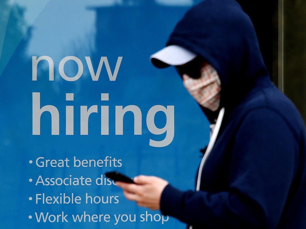 Millions of gig workers have come to depend on a government lifeline that's set to expire at the end of the year. Above, a man wearing a face mask walks past a sign saying 