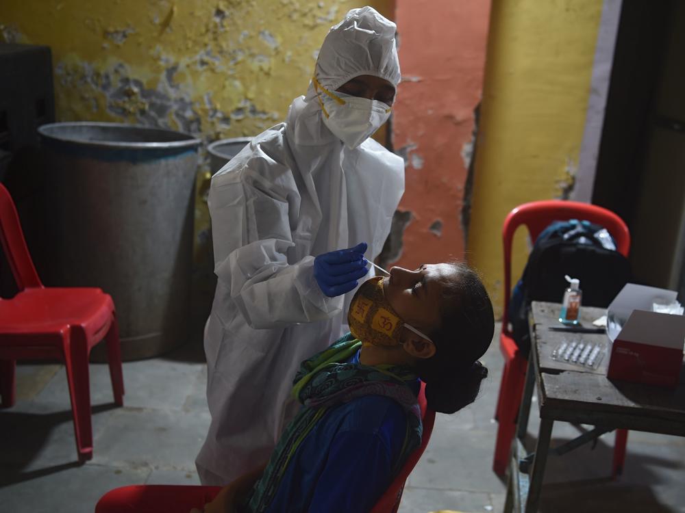 A health worker wearing protective gear collects a swab sample during a medical screening for the coronavirus in Mumbai on Wednesday. The number of registered coronavirus cases passed 5 million on Wednesday.