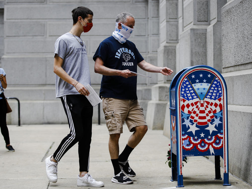 Benjamin Graff, center, and his son Jacob Graff, 19, drop off their mail-in ballots for the Pennsylvania primary election, in Philadelphia, on June 2, 2020. The state Supreme Court affirmed Thursday that counties may use drop boxes for voters casting mail-in ballots.