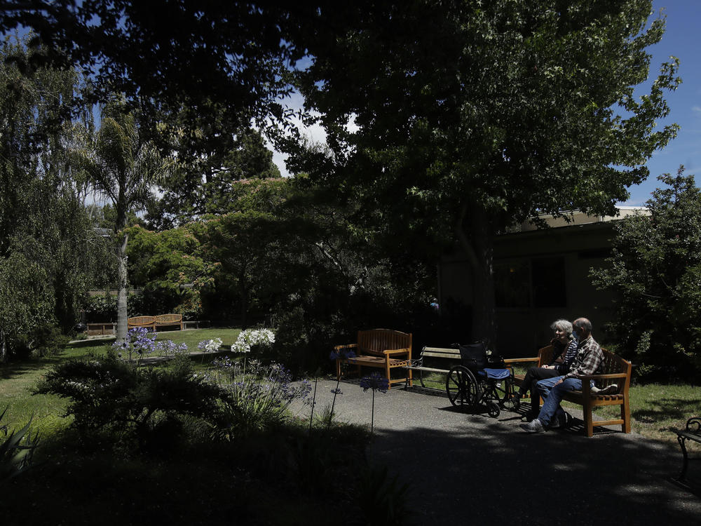 Larry Yarbroff visits his wife Mary at Chaparral House in Berkeley, Calif. in July. California health authorities had allowed some visits to resume, and now federal regulators are doing the same, with measures to try to block the spread of the coronavirus.