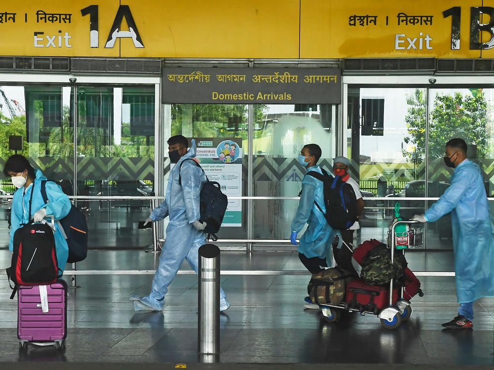 Air passengers wearing practically full-body coveralls at the Netaji Subhas Chandra Bose International Airport in India.
