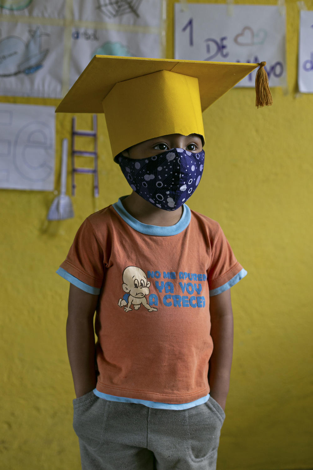 Gael Pin, 4, wears a cap and mask for the closing ceremony of his school year. Because Gael's family doesn't have an internet connection, they plan to watch the ceremony at their neighbor's house. <em>June 18. Cotogchoa, Ecuador.</em>