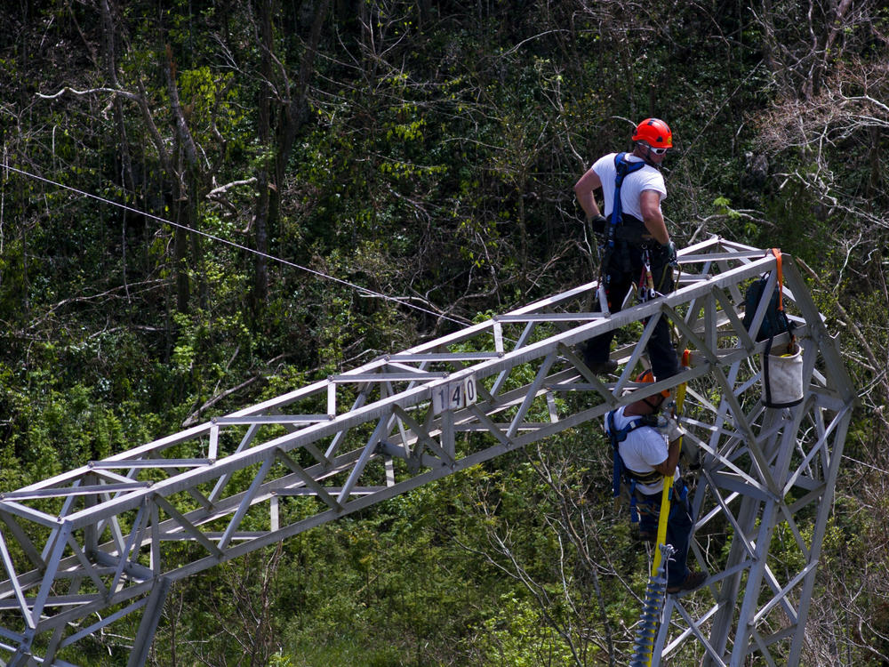 Workers restore power lines damaged by Hurricane Maria in Barceloneta, Puerto Rico, in 2017. The Trump administration says it will award nearly $13 billion in infrastructure grants to help the island recover from the storm that hit three years ago.