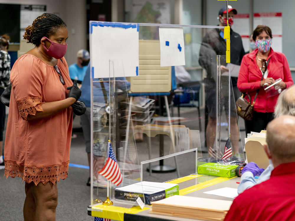 A voter stands by for her ballot as people wait more than four hours for early voting Friday in Fairfax, Va.