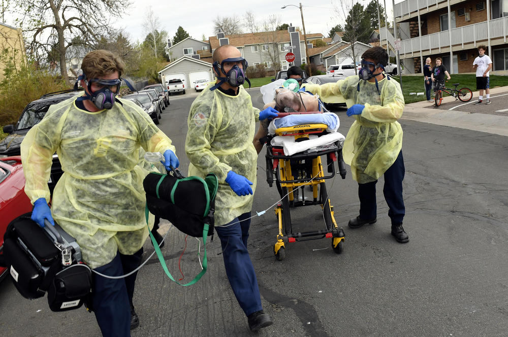 Firefighters in Littleton, Colo., move a patient on a gurney to an ambulance to take him to the hospital in May.