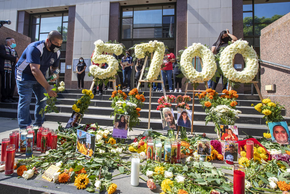 A man places a white rose on the ground last month at a memorial in downtown Los Angeles to honor the Angelenos who lost their lives due to the coronavirus.