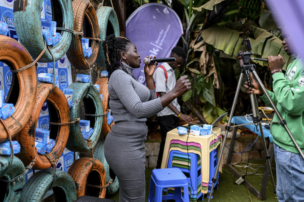 Musician Joy Bigo performs for a Facebook Live event staged by Name Experience. The popular show, attended most weeks by lots of young men, has been streaming live recordings since the pandemic began. <em>August 8. Kibera, Kenya.</em>