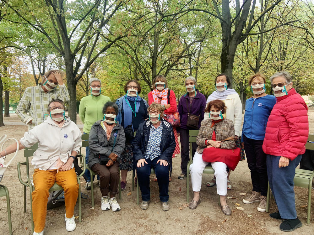 Suzy Margueron (seated, center) who advocates for people with hearing loss, likes to gather with friends in Paris' Luxembourg Gardens. All have transparent masks, but say it's others who should be wearing them too.