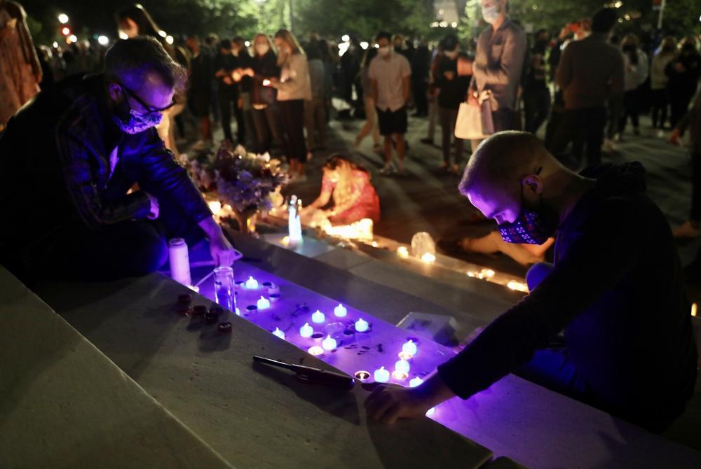 A man lights a candle on the steps of the Supreme Court.