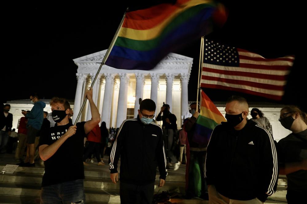 A rainbow flag is waved as people gather at a makeshift memorial for late Justice Ruth Bader Ginsburg.